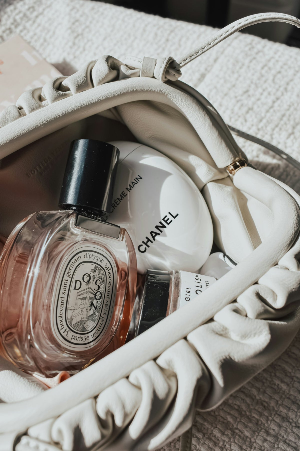 White crinkled leather bag, Diptyque perfume oil and Chanel hand cream